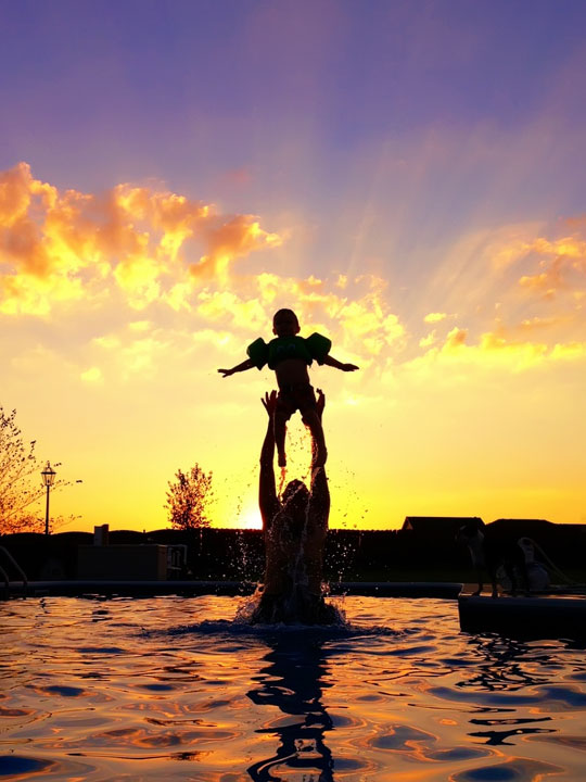Silhouettes in a Pool in Front of a Sunset Image of Silhouettes in a Pool in Front of a Sunset