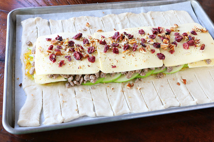 This beautiful Harvest Breakfast Braid is perfect for breakfast, brunch, or even dinner! Layers of sausage, apple, and havarti cheese make for the perfect sweet and salty combo. It's all topped with cranberries and pecans in a sweet orange marmalade glaze.