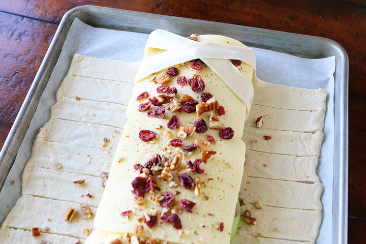 This beautiful Harvest Breakfast Braid is perfect for breakfast, brunch, or even dinner! Layers of sausage, apple, and havarti cheese make for the perfect sweet and salty combo. It's all topped with cranberries and pecans in a sweet orange marmalade glaze.