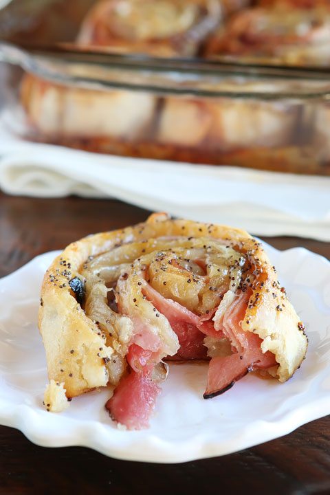 Hot Ham & Cheese Party Rolls with a Brown Sugar Poppy Seed Glaze. Perfect for taking to friends, new moms, and family because you can assemble it the night before and bake it the next day.