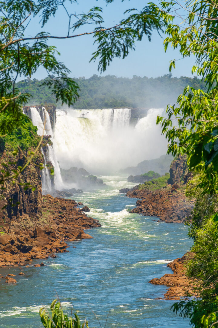 View of Iguazu Falls through trees from Argentina.